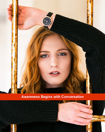 young red head woman standing behind bars, wearing watch on the inside of her wrist