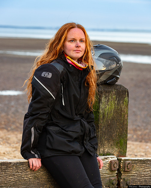 A woman wearing motorcycle gear sitting on a bench, reflecting on mental health, symbolizing support and awareness for mental health issues.