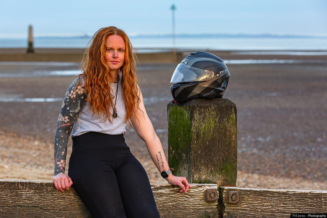 A woman sitting on the beach, wearing casual clothing, and watch inside her wrist, with a serene expression against a natural background.