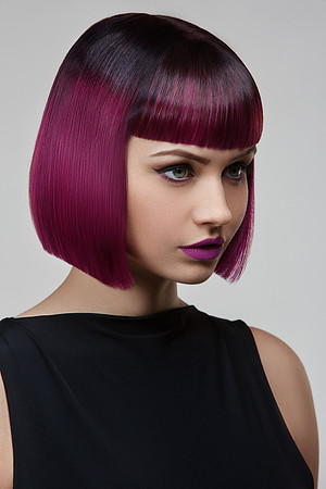Image of young woman with purple bob hair, she has flawless skin and purple lipstick