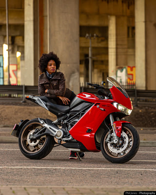 a woman leans against an electric motorcycle