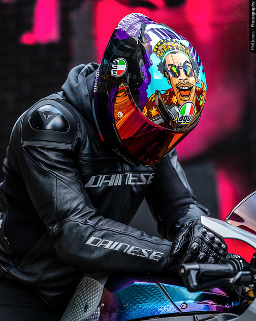 A man in a vibrant, MotoGP inspired colourful helmet, showcasing his unique and eye-catching AGV headgear.