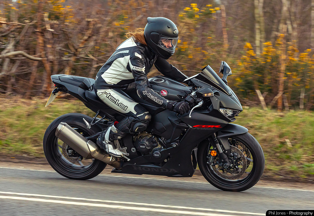 A woman rides her sports motorcycle along a sweeping road