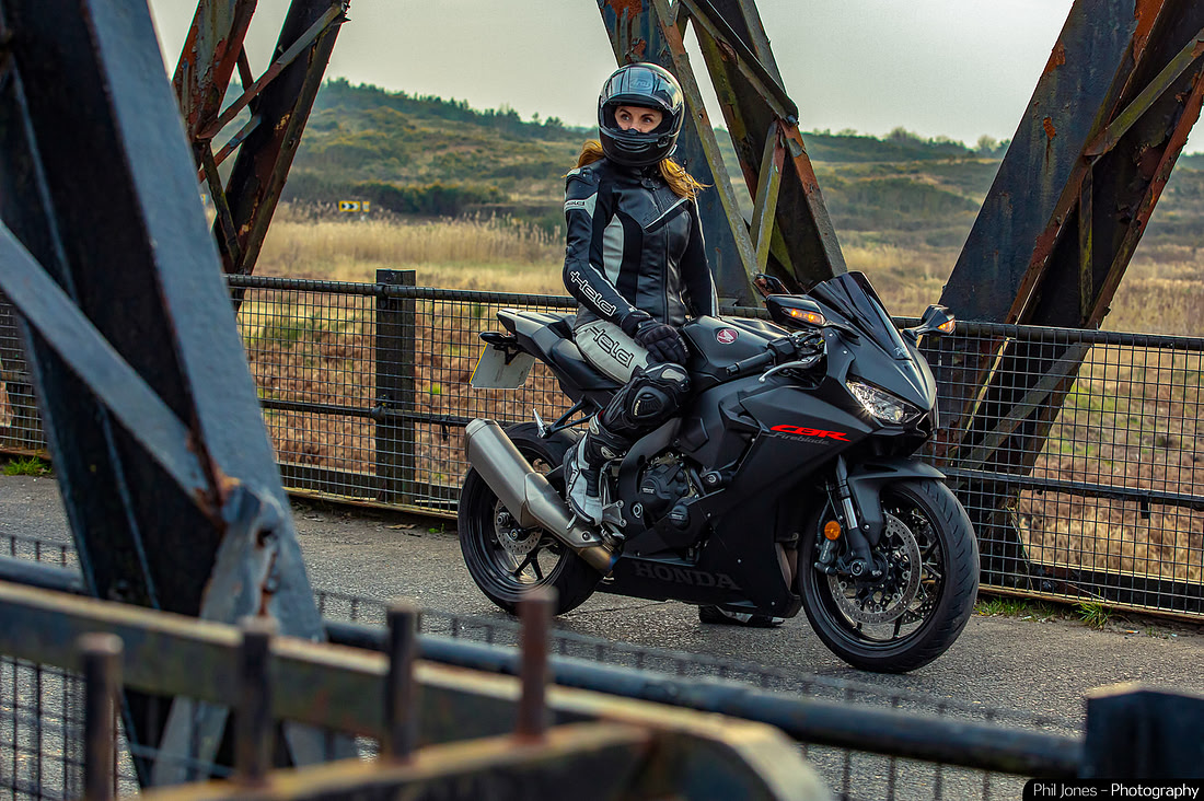 A woman sits on her sports bike parked on a construction bridge